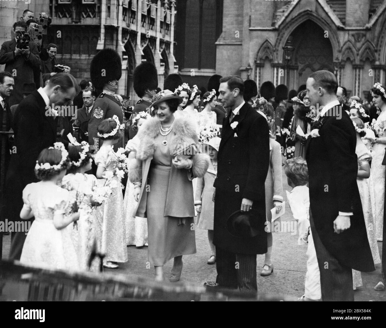 Queen Elizabeth, King George VI, Princess Margaret Rose and Princess Elizabeth (undercover) at the wedding of the Queen's niece, Miss Bowes-Lyon and Lieutenant-Colonel Thomas William Arnold Anson at Westminster Abbey. The bridesmaids are standing at the edge. Stock Photo