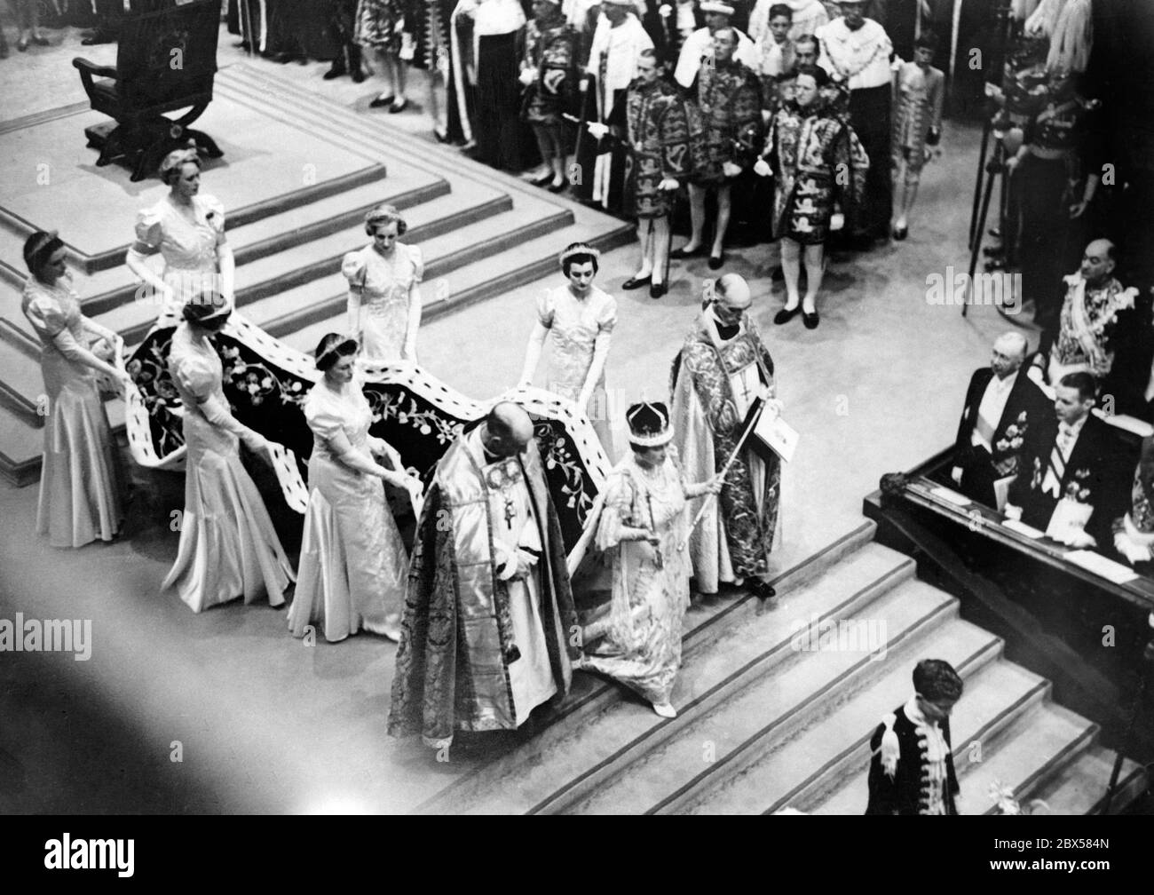Queen Elizabeth leaves Westminster Abbey after her coronation with the sceptre in her hand. Her veil is carried by six women and she is accompanied by two priests. Stock Photo