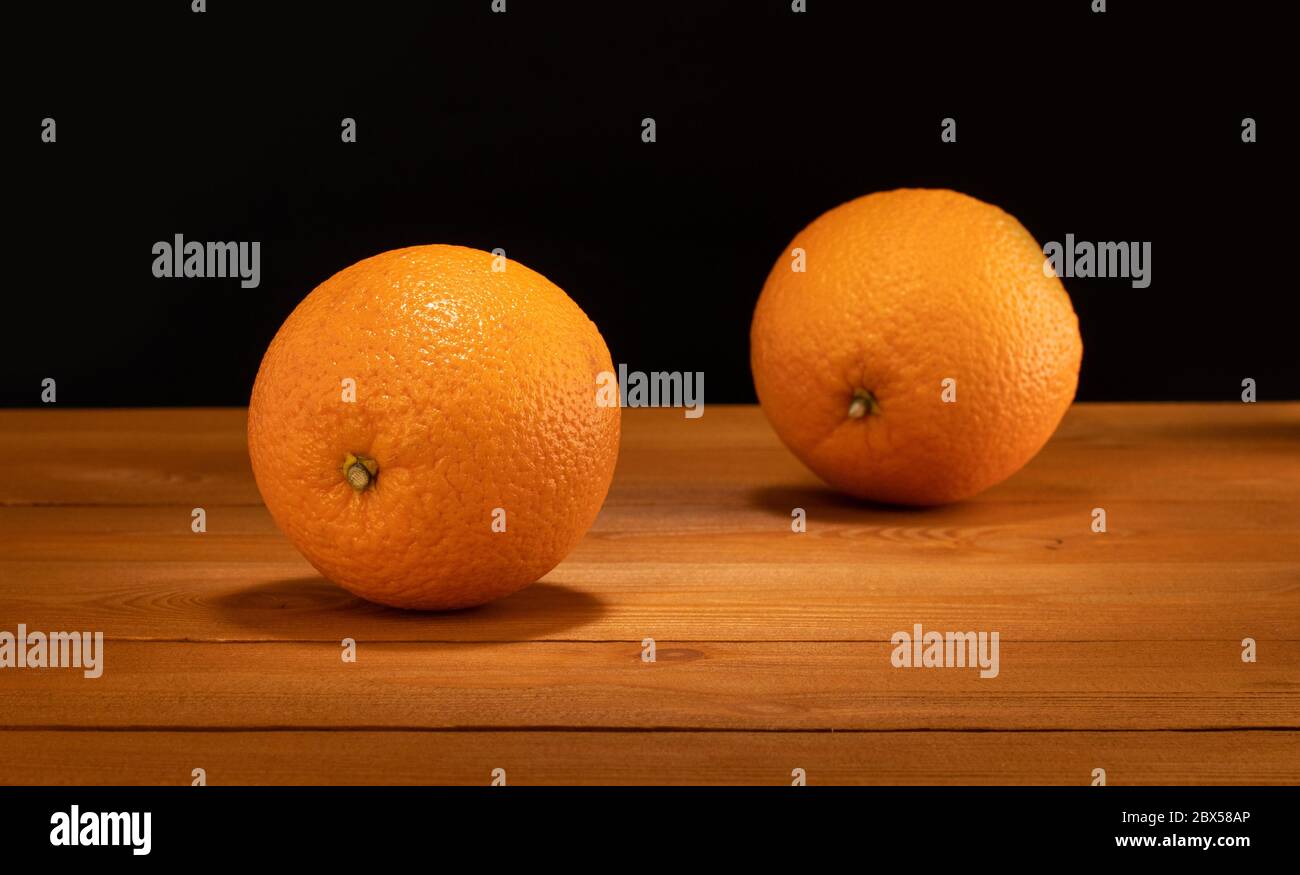 two oranges on wooden table and black background Stock Photo