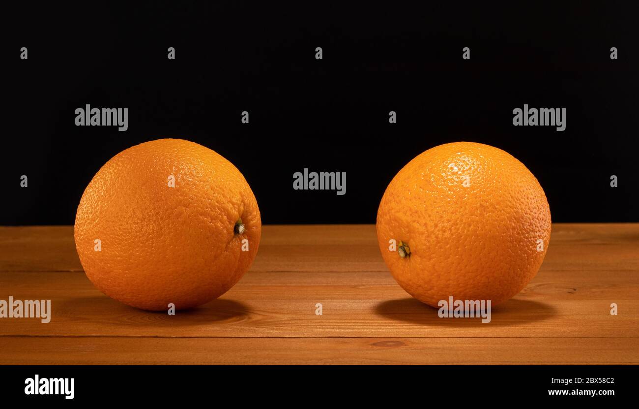 Two oranges on wooden table and black background Stock Photo
