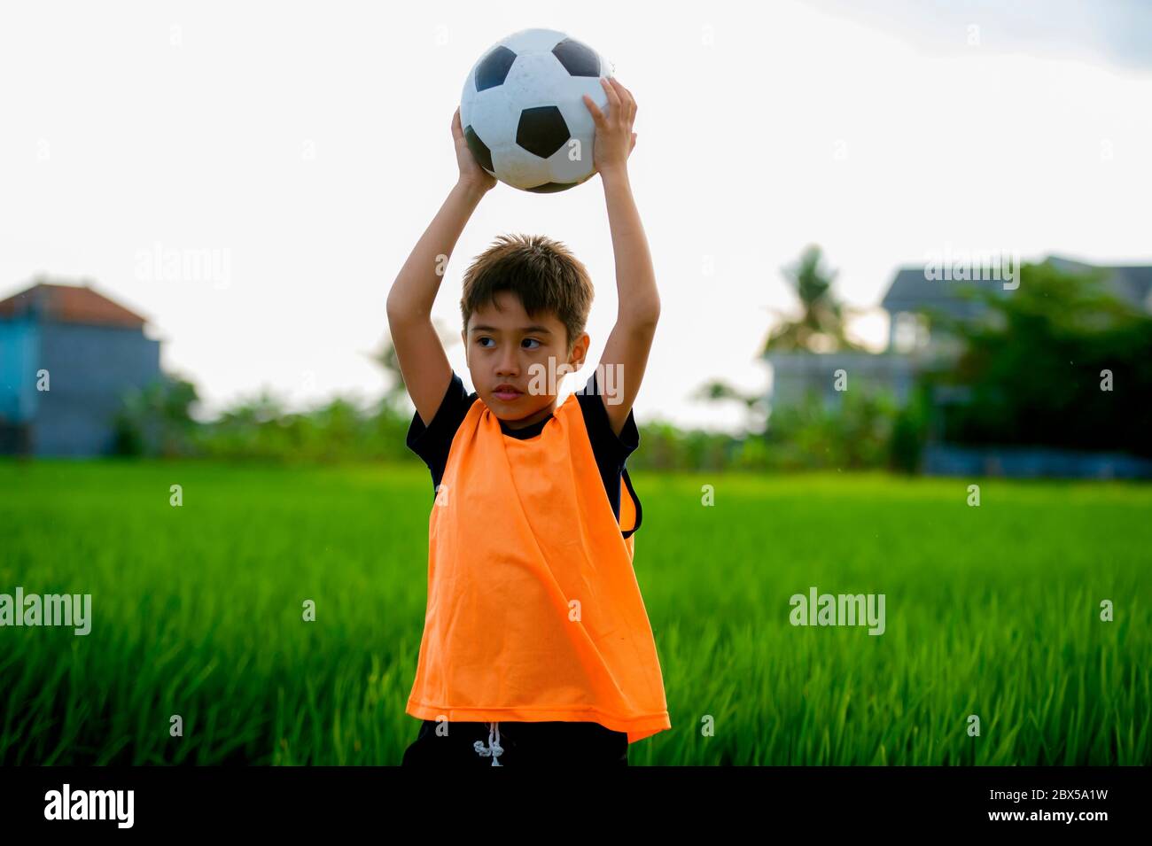 Lifestyle Portrait Of Handsome And Happy Young Boy Holding Soccer Ball Playing Football Outdoors At Green Grass Field Smiling Cheerful Wearing Trainin Stock Photo Alamy
