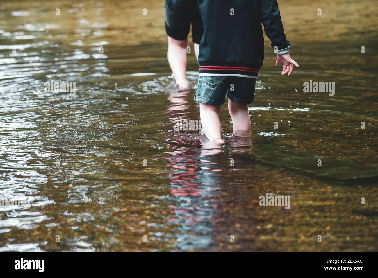 children-playing-outside-in-a-shallow-stream-paddling-in-the-water