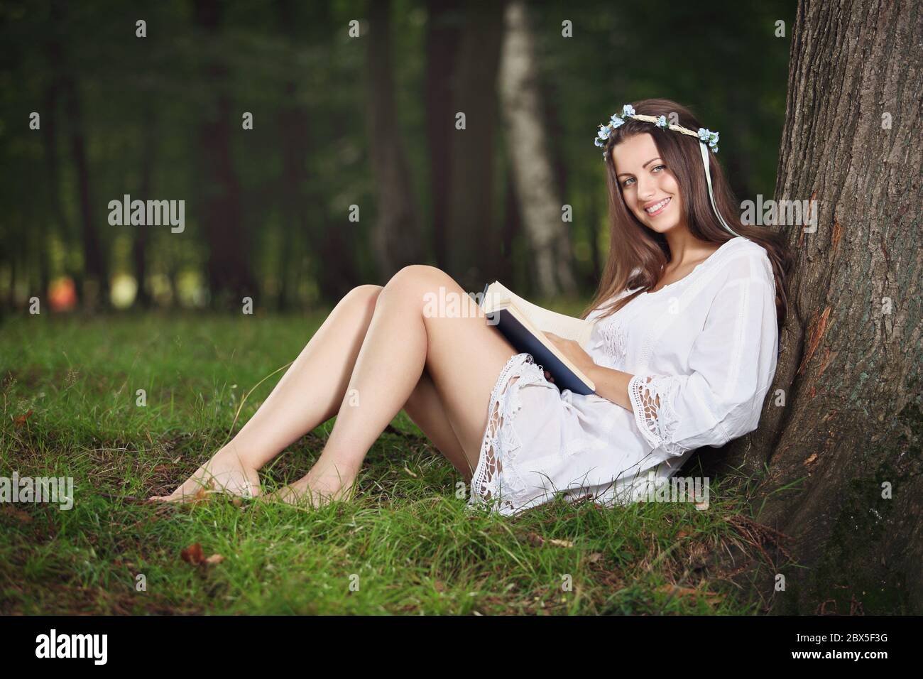 Joyful young woman reading outdoor and smiling . Relax in nature Stock Photo