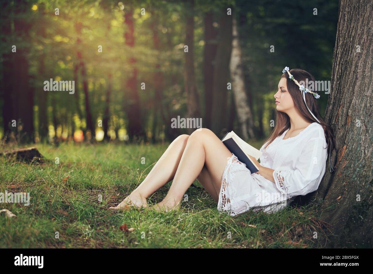Young woman reading pecefully in beautiful forest . Relax and serenity Stock Photo