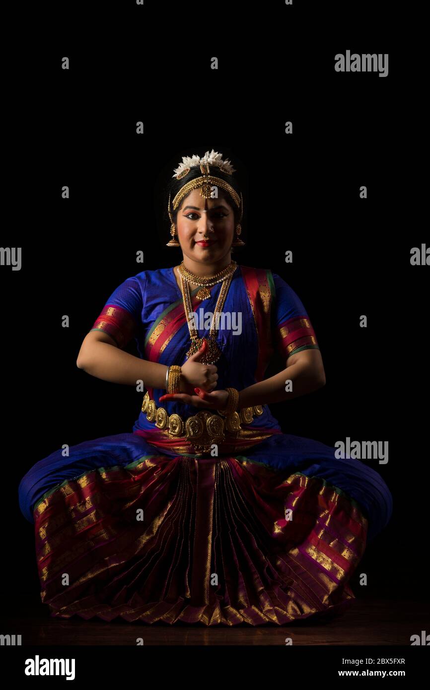 Bharatnatyam dancer in a shiva lingam pose during her performance on a dark background. Stock Photo