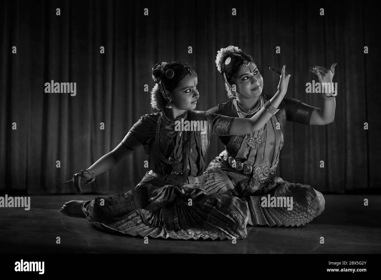 Black and white image of a bharatnatyam dancer teaching her young student. Stock Photo