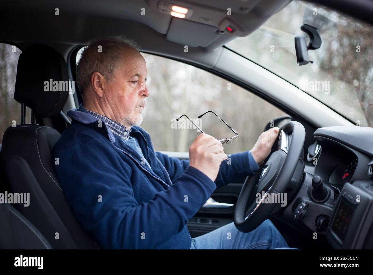 Senior man putting on glasses before driving, his eyesight is not good
