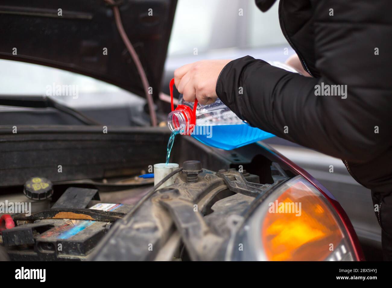 Detail on pouring antifreeze liquid screen wash into dirty car from