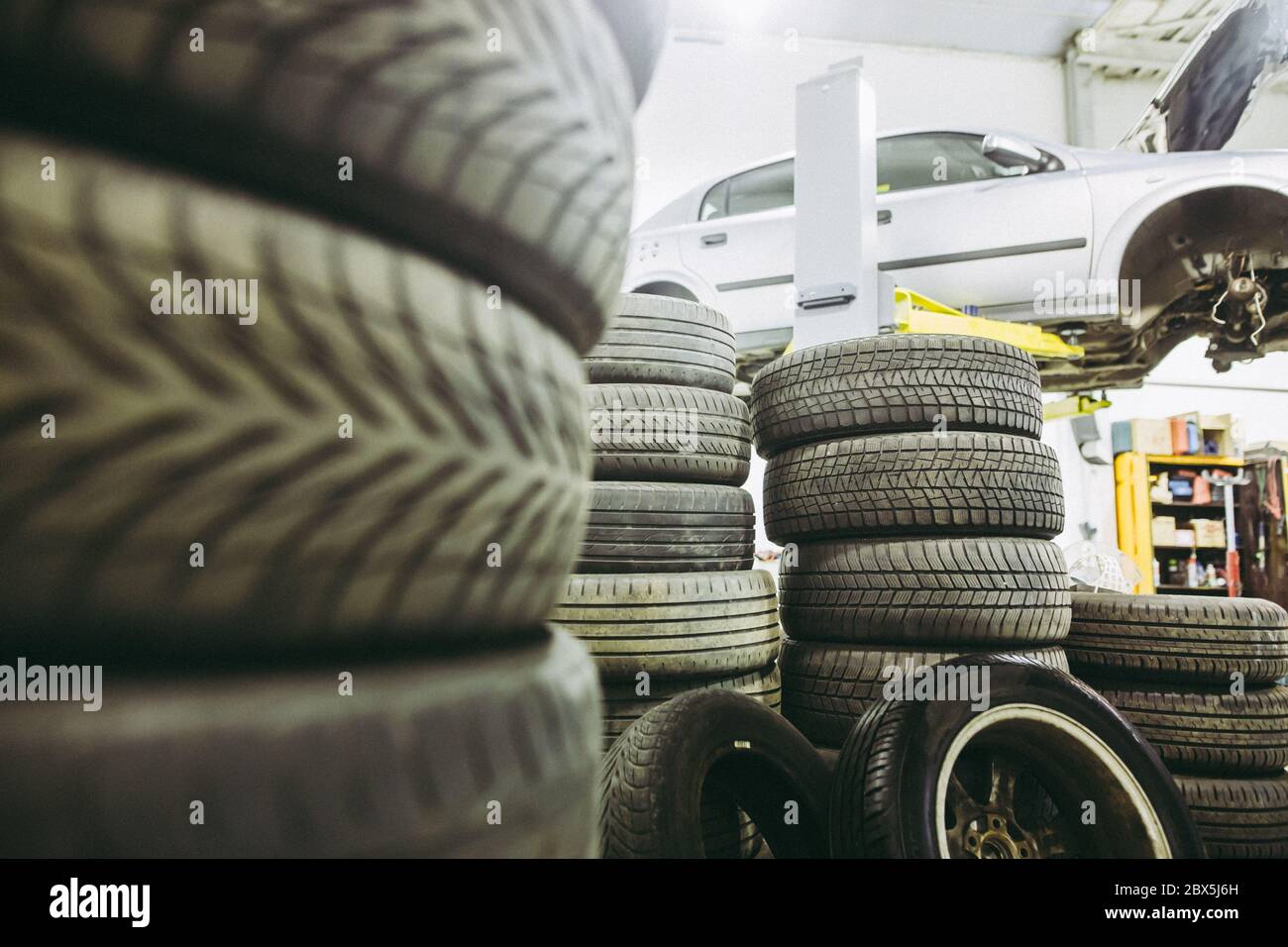 View to car service, a lot of wheels ready for changing and car on the hydraulic jack, car service center Stock Photo