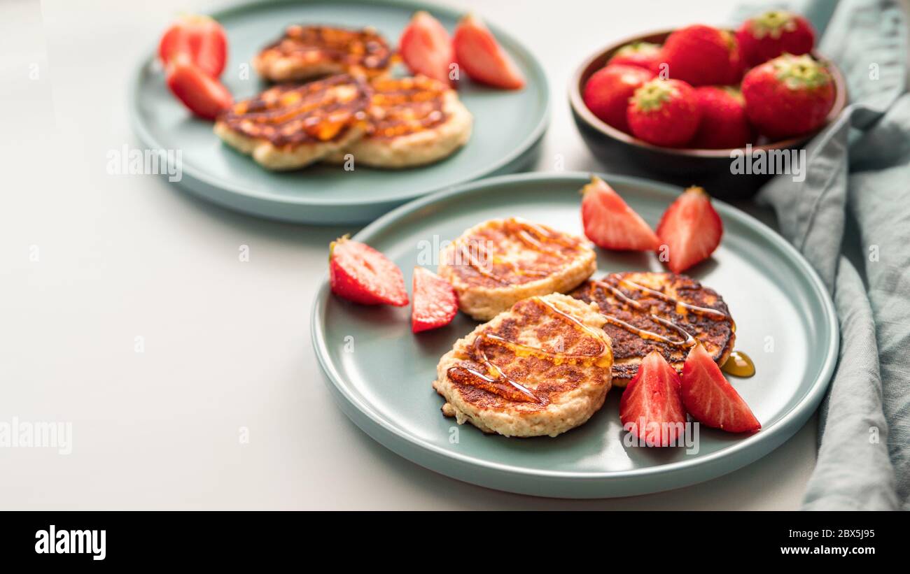 Sweet cheese pancakes on plate served strawberries. Cottage cheese pancakes, syrniki, ricotta fritters, curd fritters, Copy space for text or design. Stock Photo