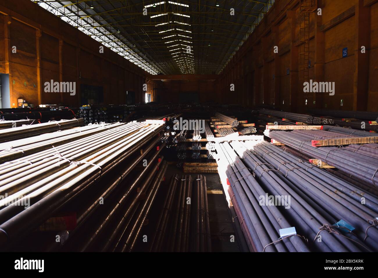 Steel round bar in bundles stacks inside a warehouse with overhead crane. Stock Photo