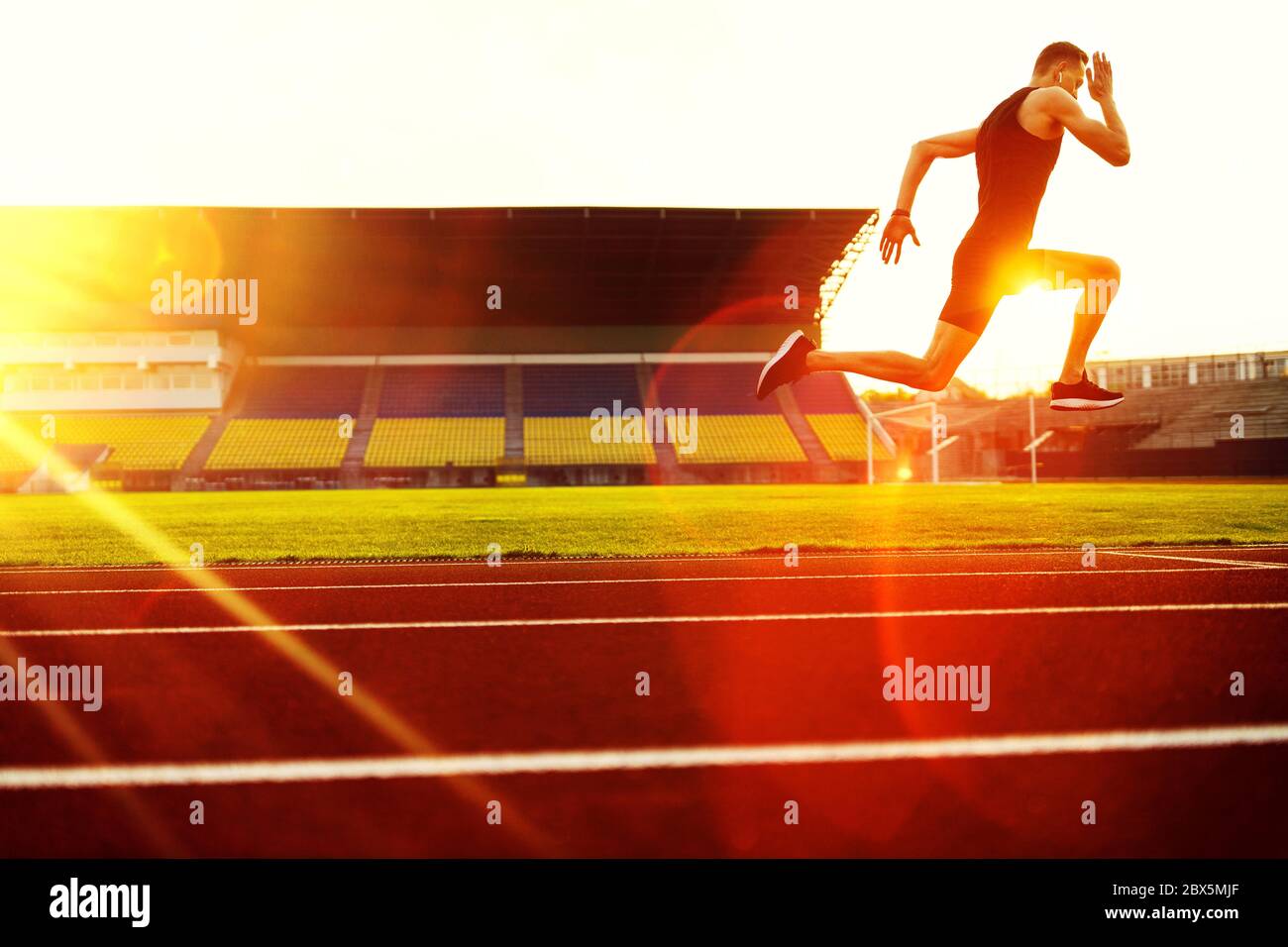 Young handsome athlete running at the stadium at sunset Stock Photo - Alamy