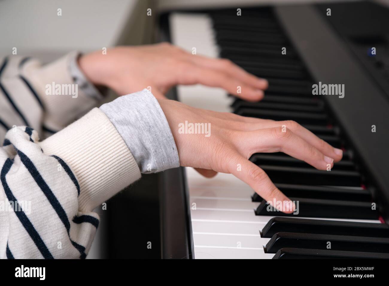 Closeup of teenager playing piano in home music studio. Girl having