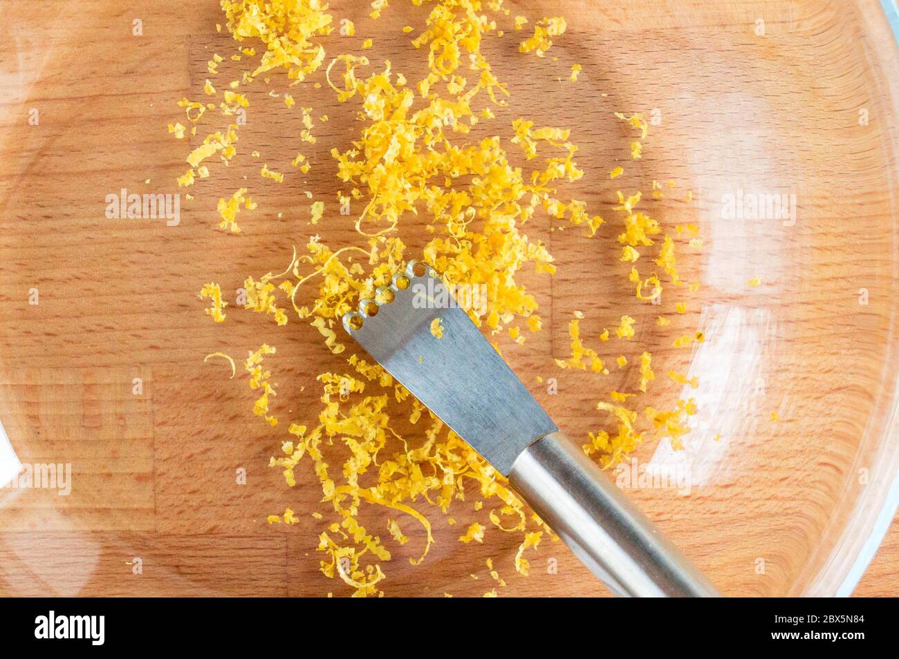 Knife for zest. Finely chopped lemon zest in a transparent bowl. Small hole knife. Stock Photo