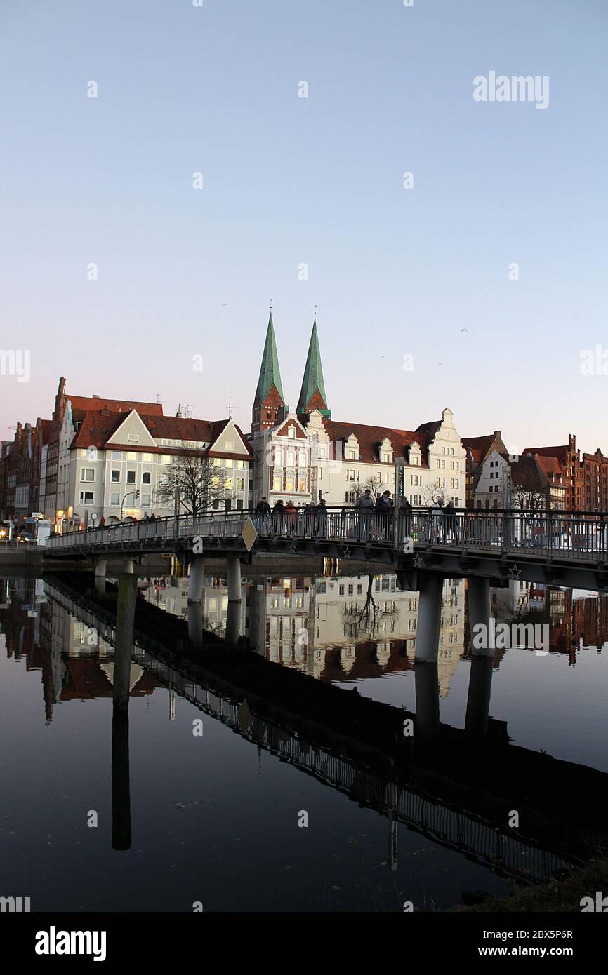 Luebeck, Germany - 02 December 2016: View of Lübeck and a pedestrian bridge over the river Trave at dusk. The bridge is at 'An der Untertrave' Stock Photo