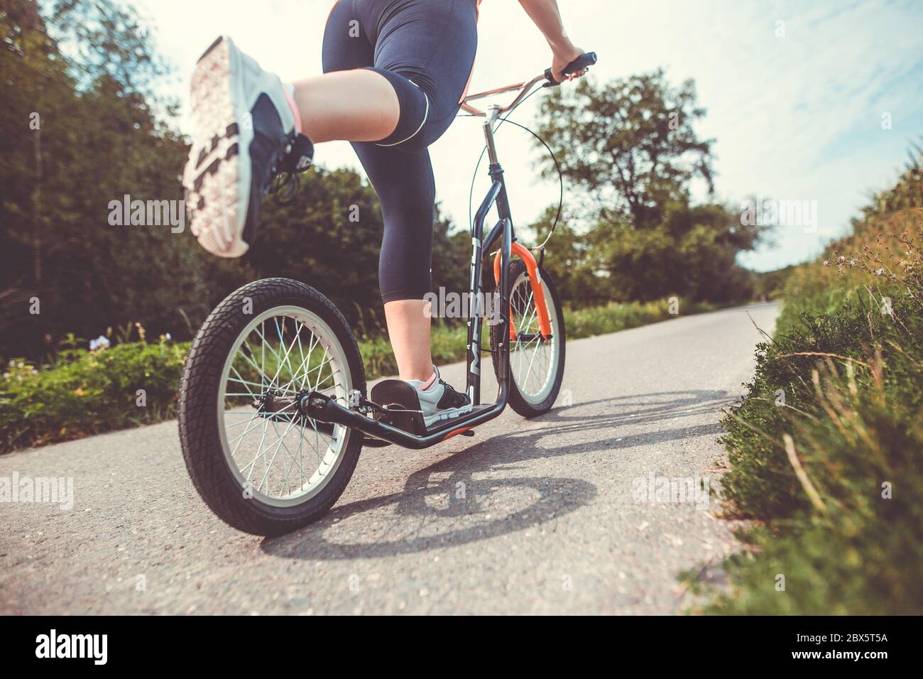 Kick Riding Cycle Pretty young brunette woman riding on a push, kick sport on a bike path ...