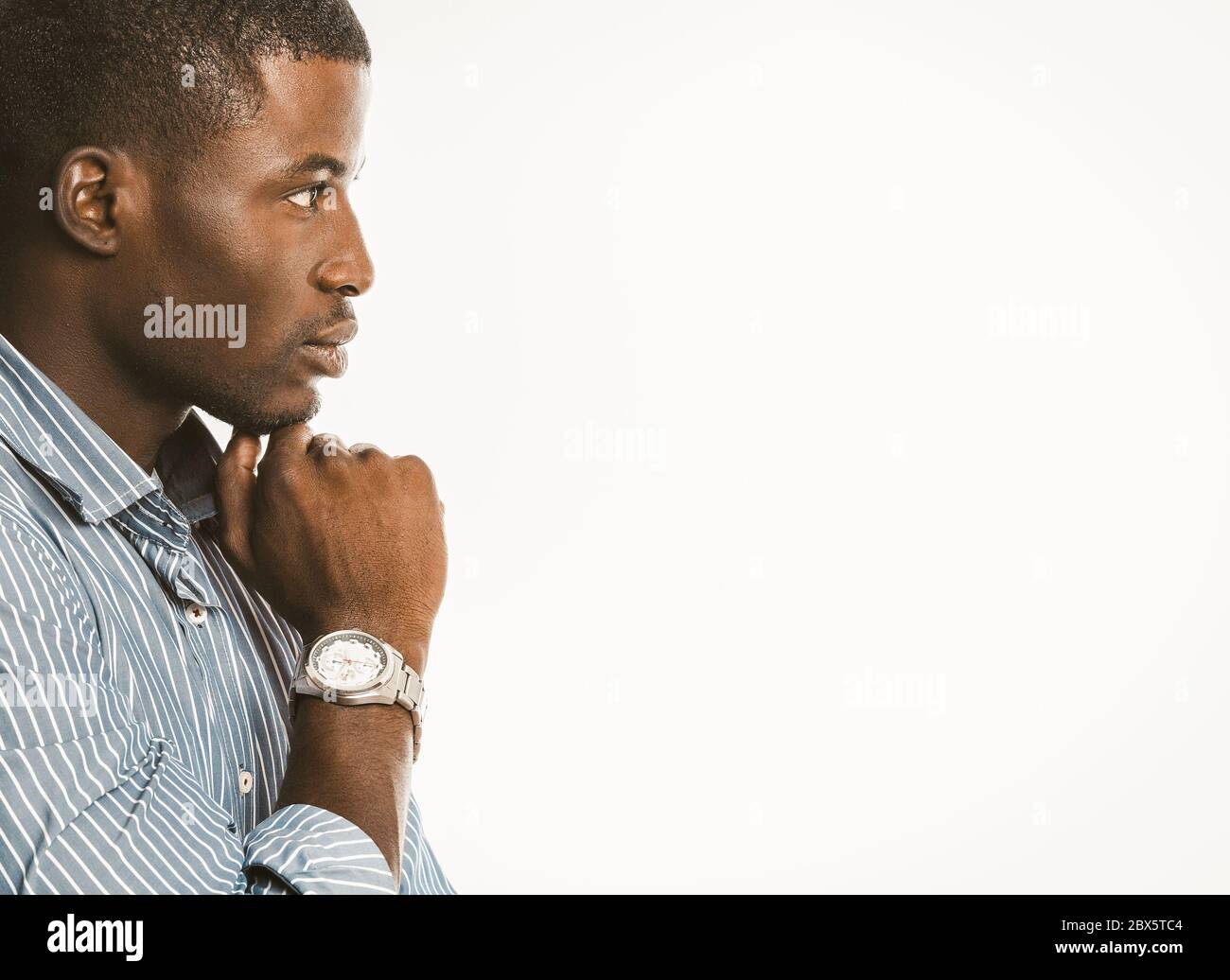 Pensive African American businessman touches his chin with hand with luxury wristwatch. Creative guy generating of idea on white background. Copy Stock Photo