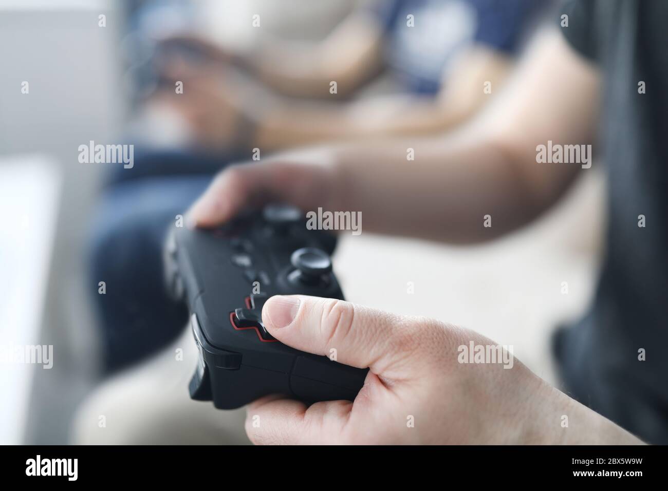 Two male friends play video games against home background Stock Photo