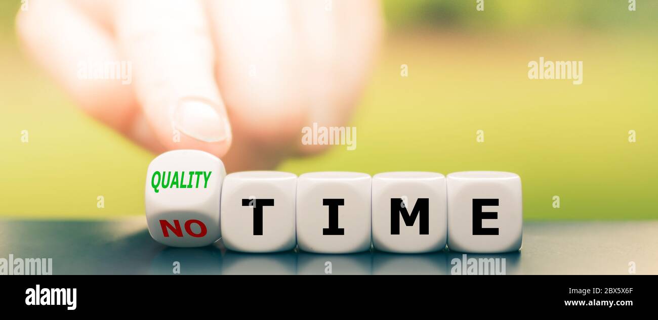 Hand turns dice and changes the expression 'no time' to 'quality time'. Stock Photo