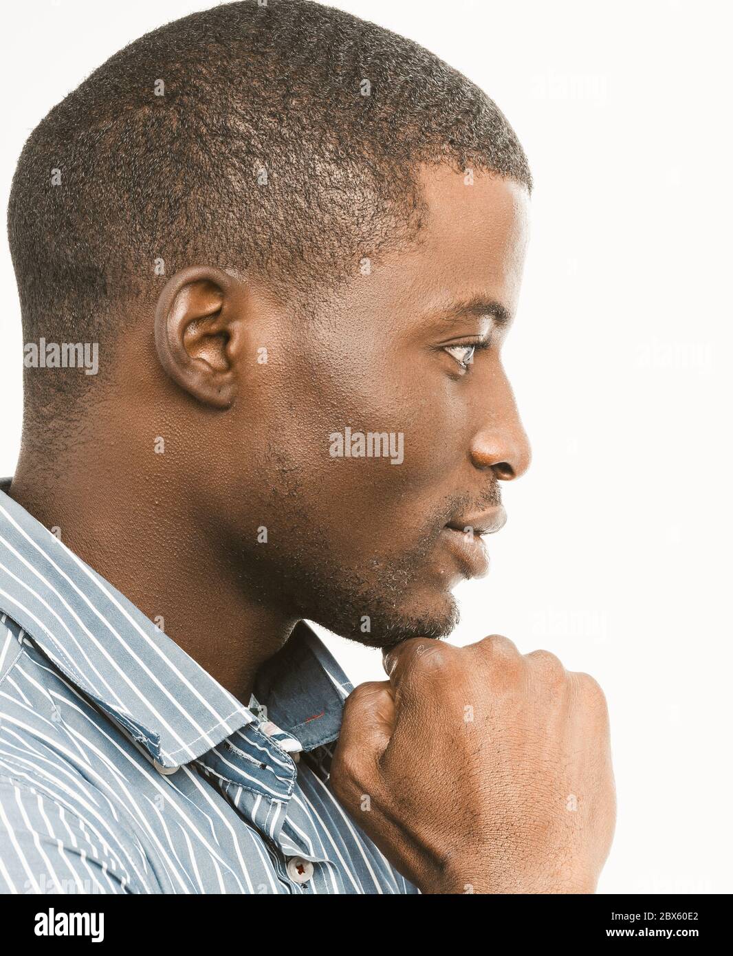 Thoughtful African American man touches his chin looking to the side. Profile view of short-haired handsome guy on white background. Close-up portrait Stock Photo