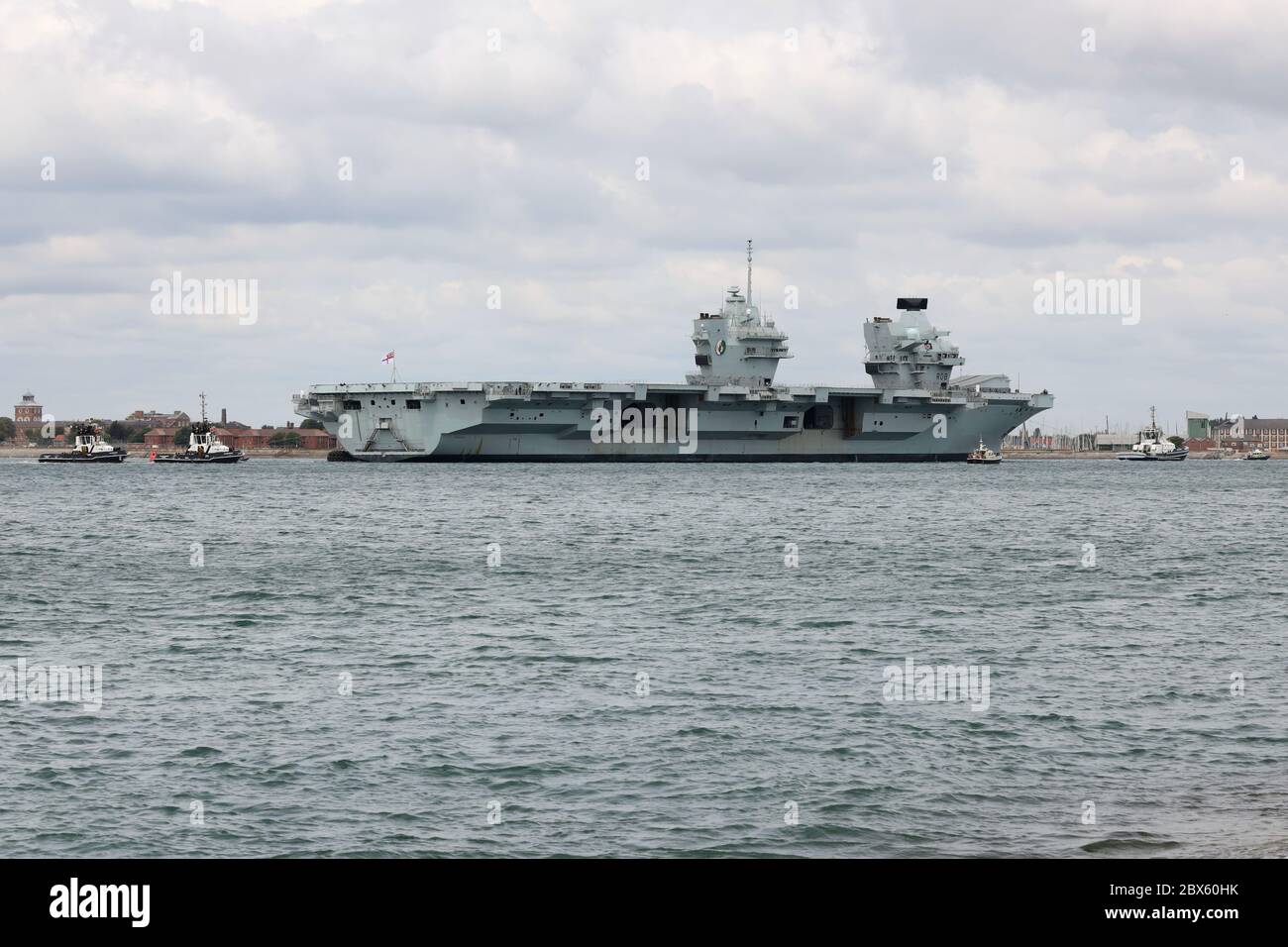 A small flotilla of tugs guide the Royal Navy aircraft carrier HMS QUEEN ELIZABETH towards the harbour entrance this morning Stock Photo