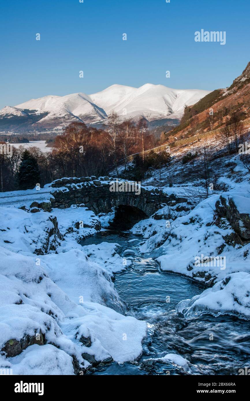 A snow covered winter scene at Ashness Bridge with Skiddaw mountain in ...