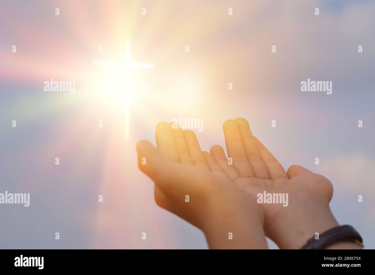 Hands open palm up worship over sunrise background. Catholic praying for blessing from god. Stock Photo