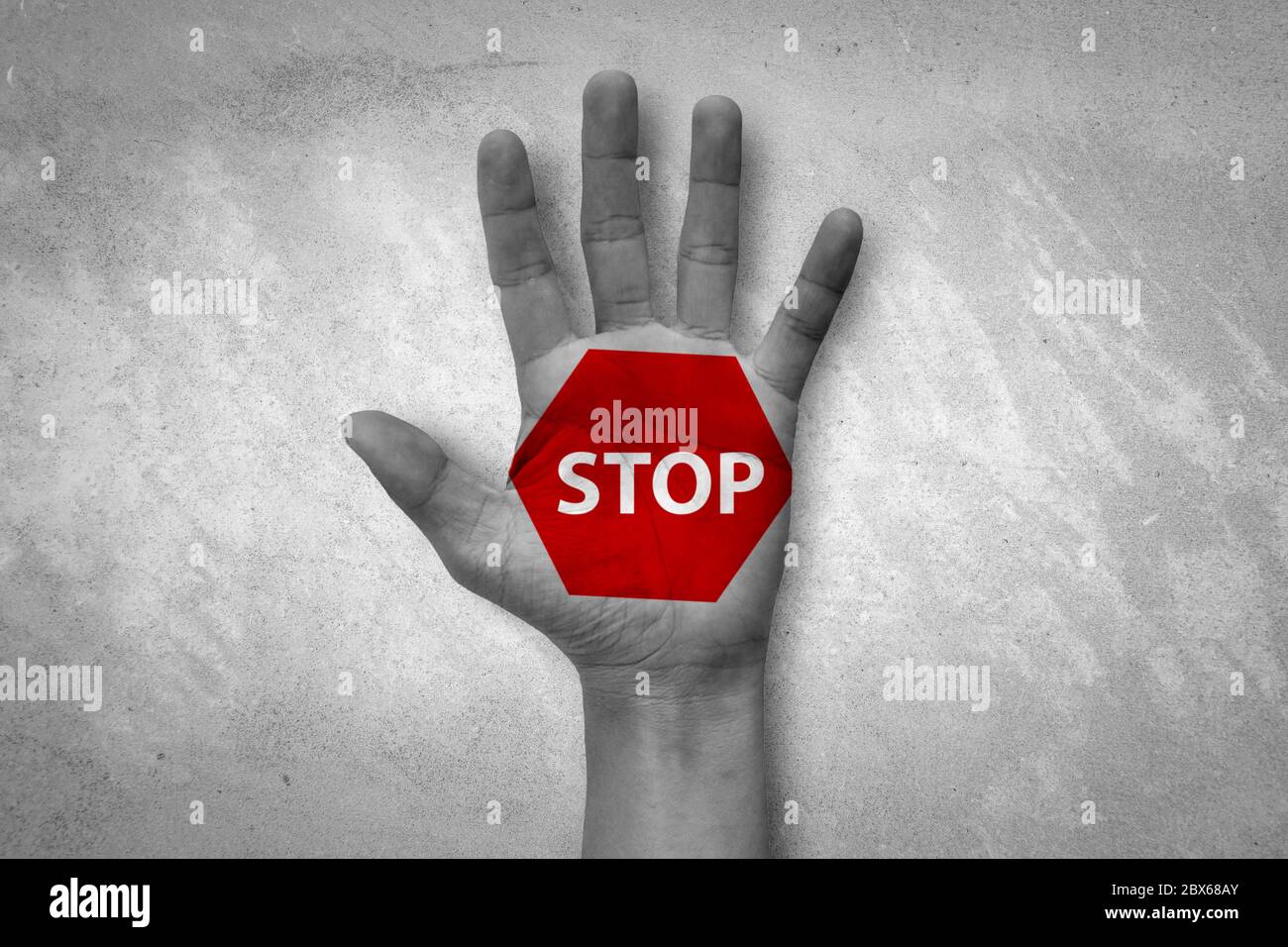 Hand raised with stop sign painted. Emotional black and white photo with red symbol. Stock Photo