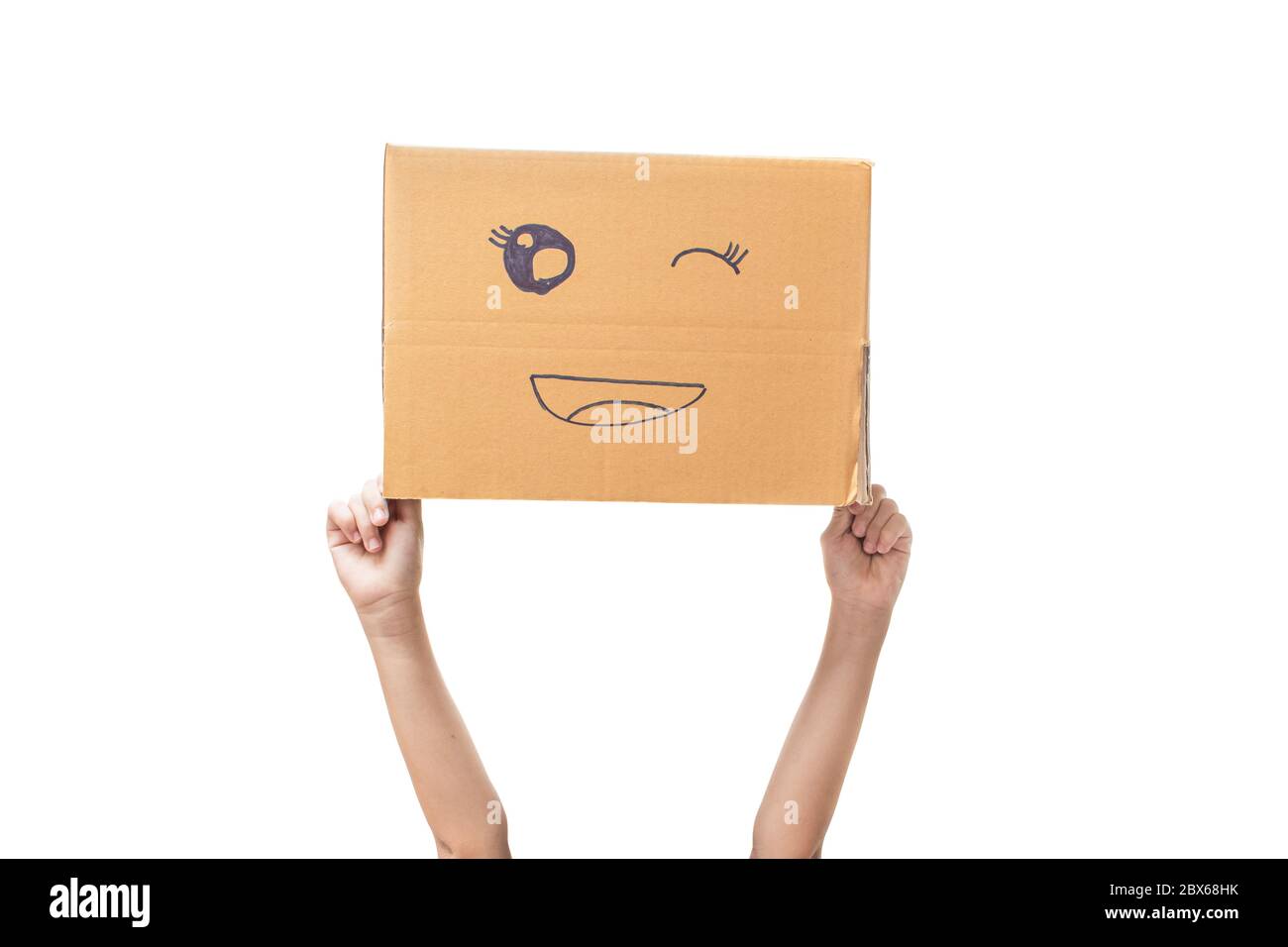 Child hand holding a cardboard box with smiley face isolated on white background. with clipping path. Stock Photo