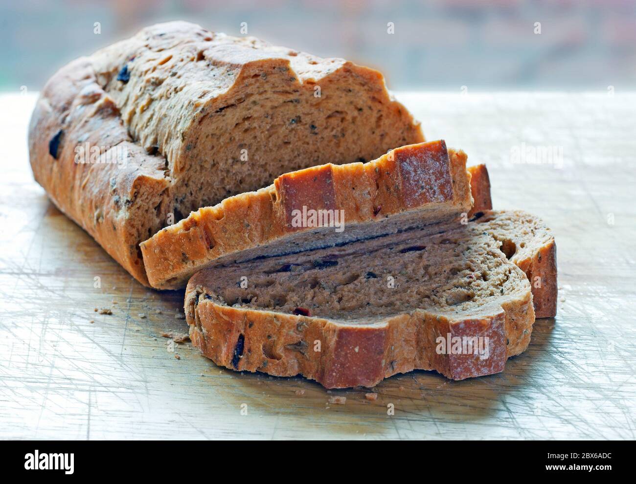 Mediterranean sun dried tomato and olive bread with a shallow depth of field on a cutting board with two sliced pieces and crumbs Stock Photo