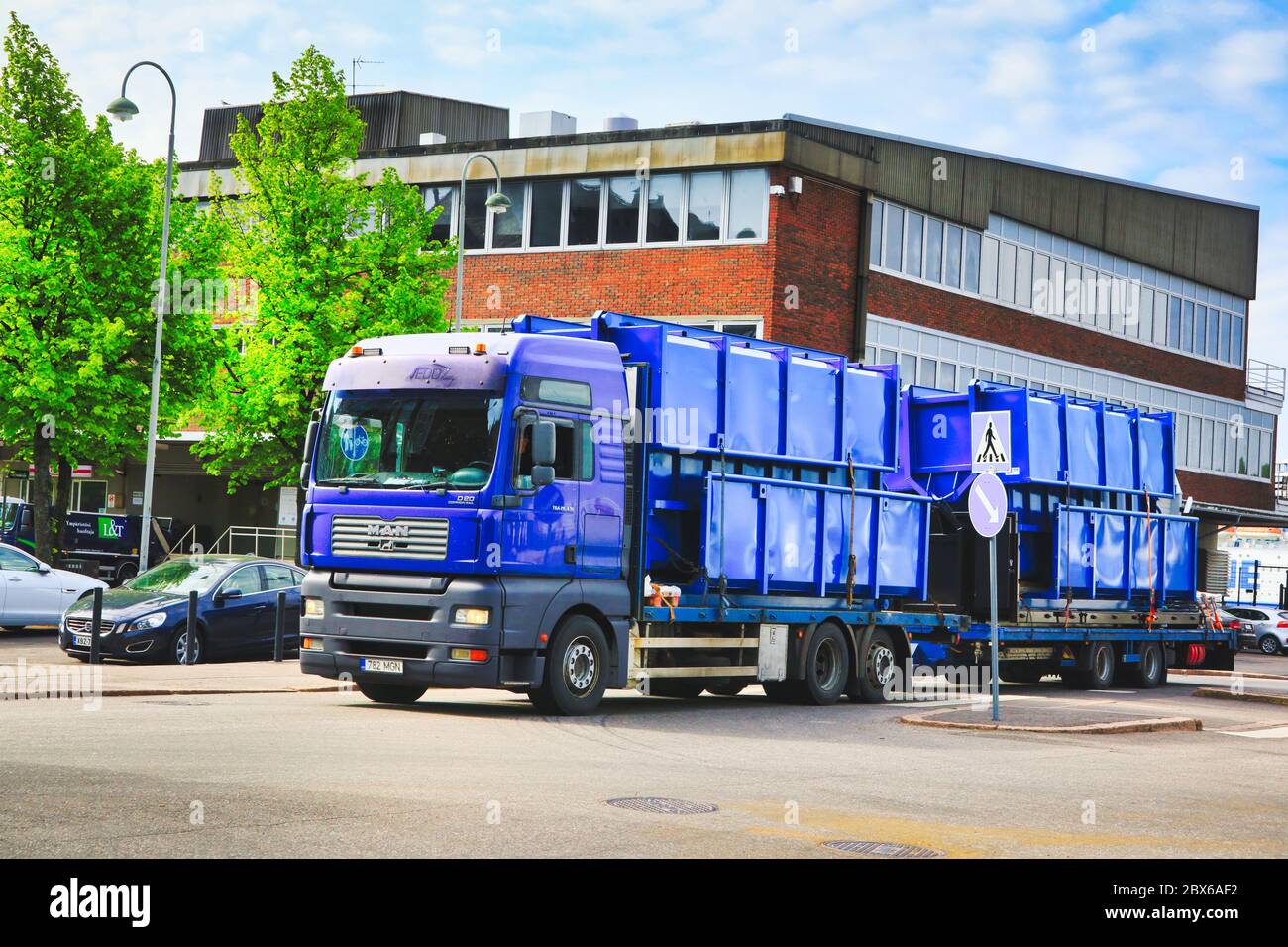 Blue MAN TGA truck transports a load of dumpsters on trailer, exits Port of Helsinki, Finland. May 3, 2020. Stock Photo