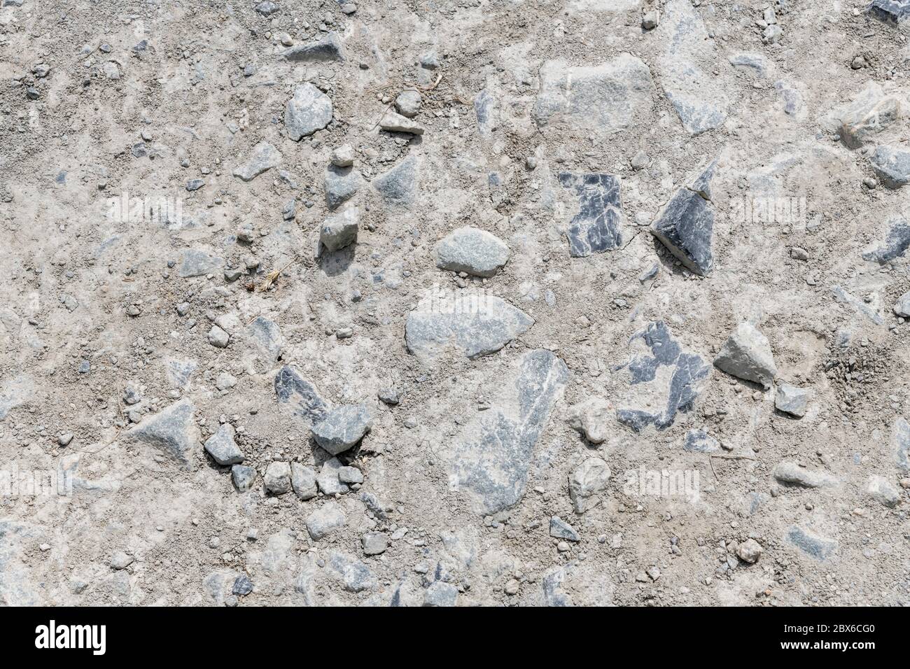 Rough gravelly and stony dirt track caked with mud & baked dry in summer sun. Fall on stony ground metaphor, bumpy ride, uneven surface, rough texture Stock Photo