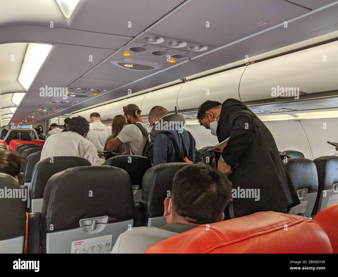 Passengers wearing masks queue to disembark a domestic Air Asia flight to Bangkok. Thailand has resumed domestic flight Stock Photo