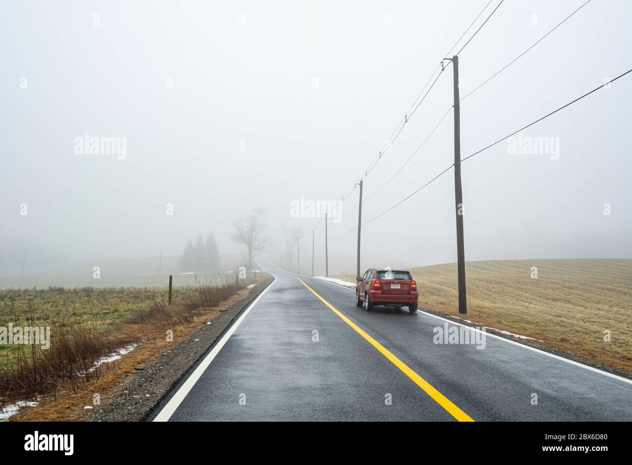 One red car drives down a lonely road Stock Photo