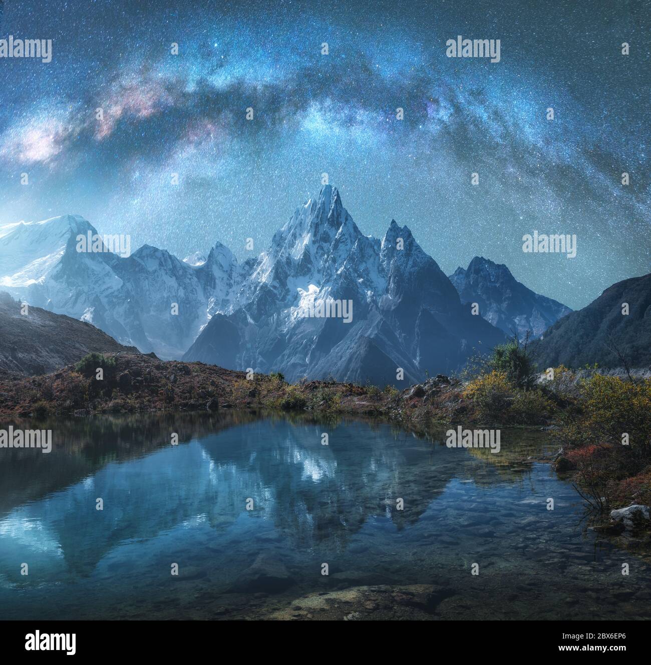Milky Way over snowy mountains and lake at night. Landscape Stock Photo