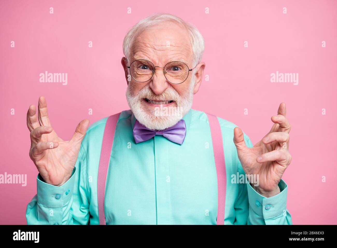 Closeup photo of mad grandpa grimace negative facial expression outraged raise hands grinning wear specs mint shirt suspenders violet bow tie isolated Stock Photo