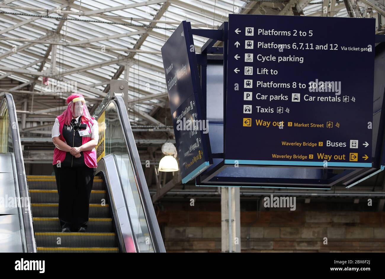 A customer service assistant at Edinburgh Waverley Station wears a protective mask as Scotland moves into phase one of the Scottish Government's plan for gradually lifting lockdown. Stock Photo