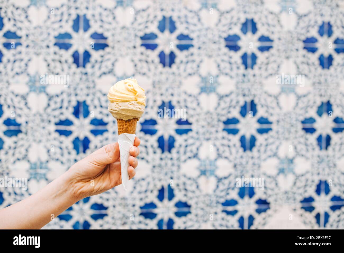 Female hand holding ice cream cone on blurred white blue background ...