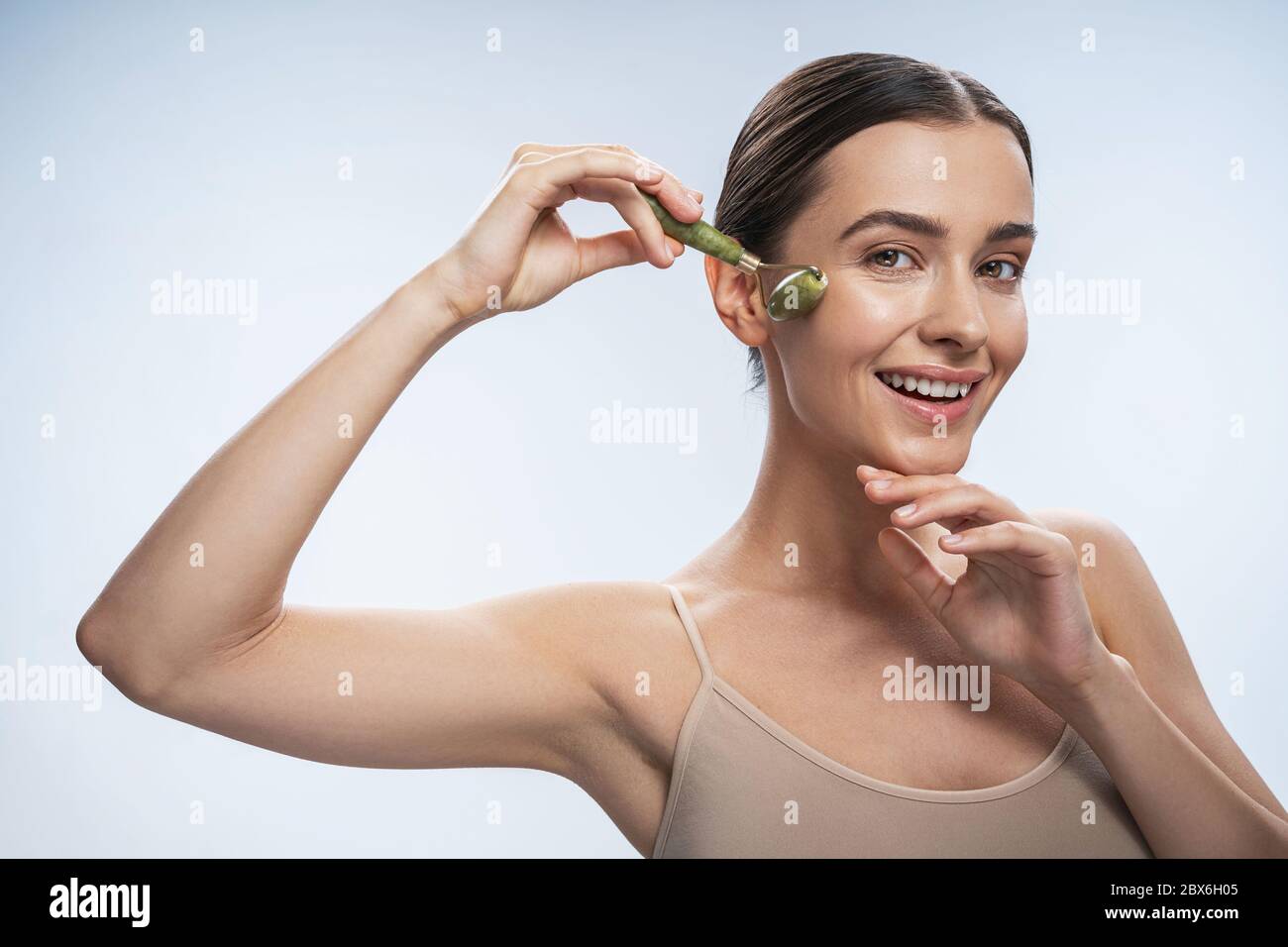 High-spirited lady with a jade roller looking forward Stock Photo
