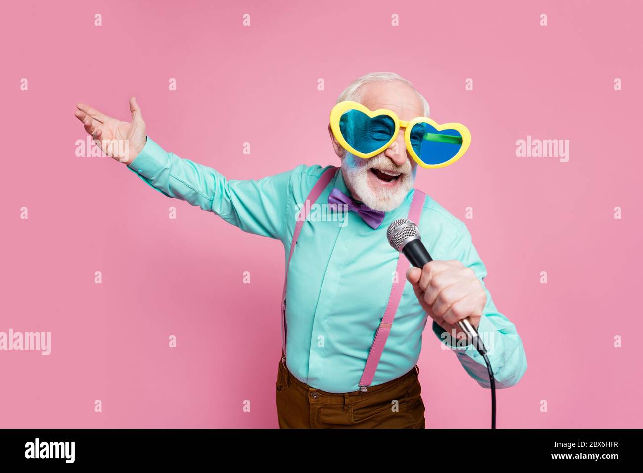 Photo of funny stylish grandpa positive emotions holding karaoke microphone  singing party songs wear cool specs shirt suspenders bow tie trousers Stock  Photo - Alamy