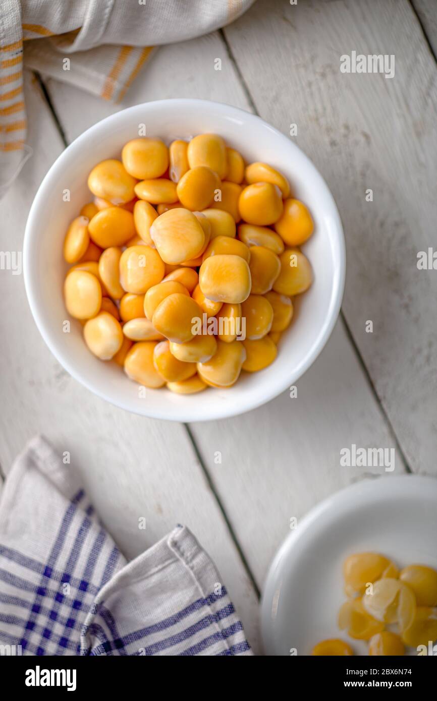 Lupins in a Bowl on a White Wooden Table with Napkins Stock Photo