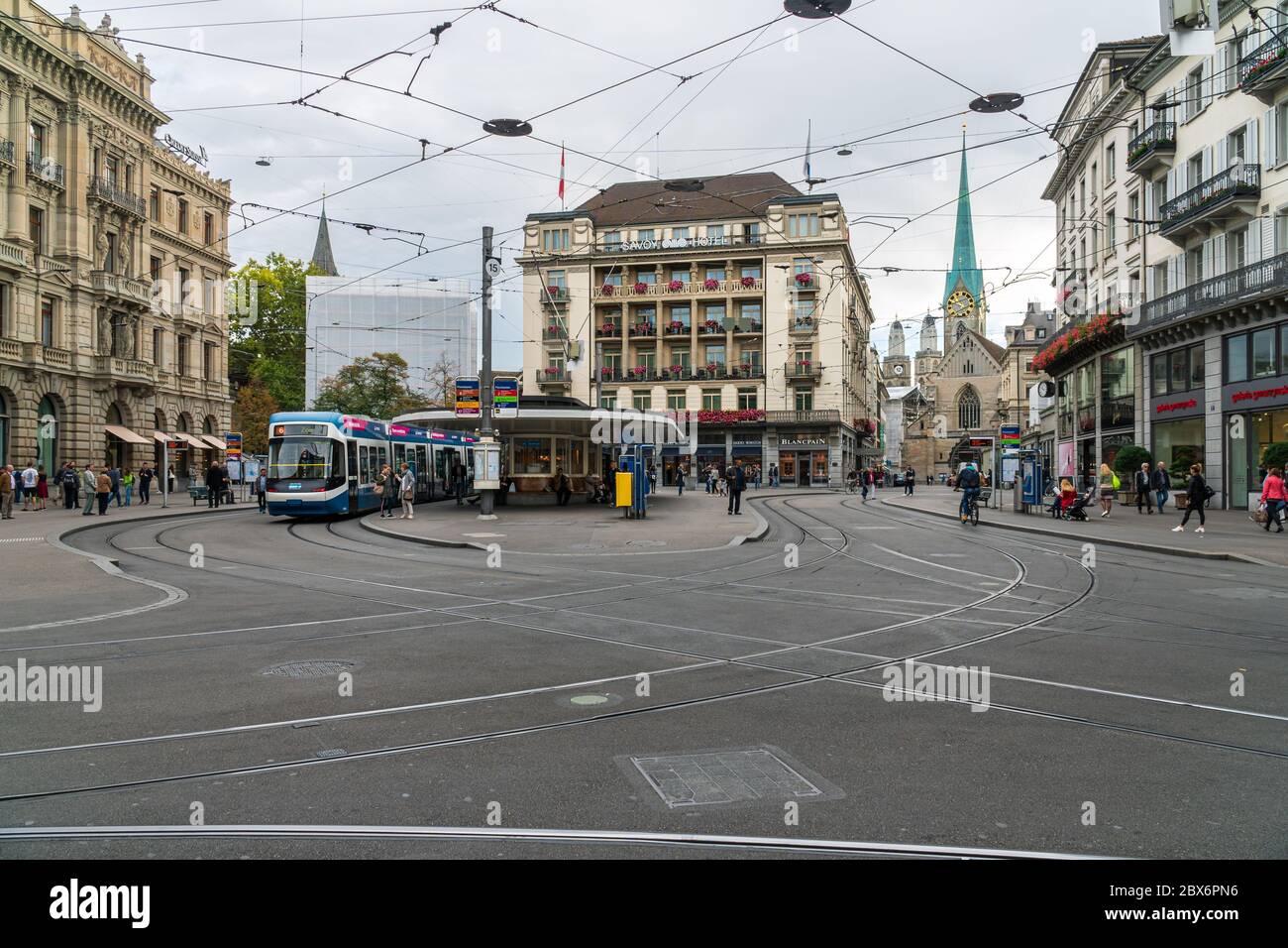 Zurich, Switzerland - October 6, 2018: People visiting the Paradeplatz square with its famous tram station, Savoy Hotel and a view to Fraumünster Stock Photo