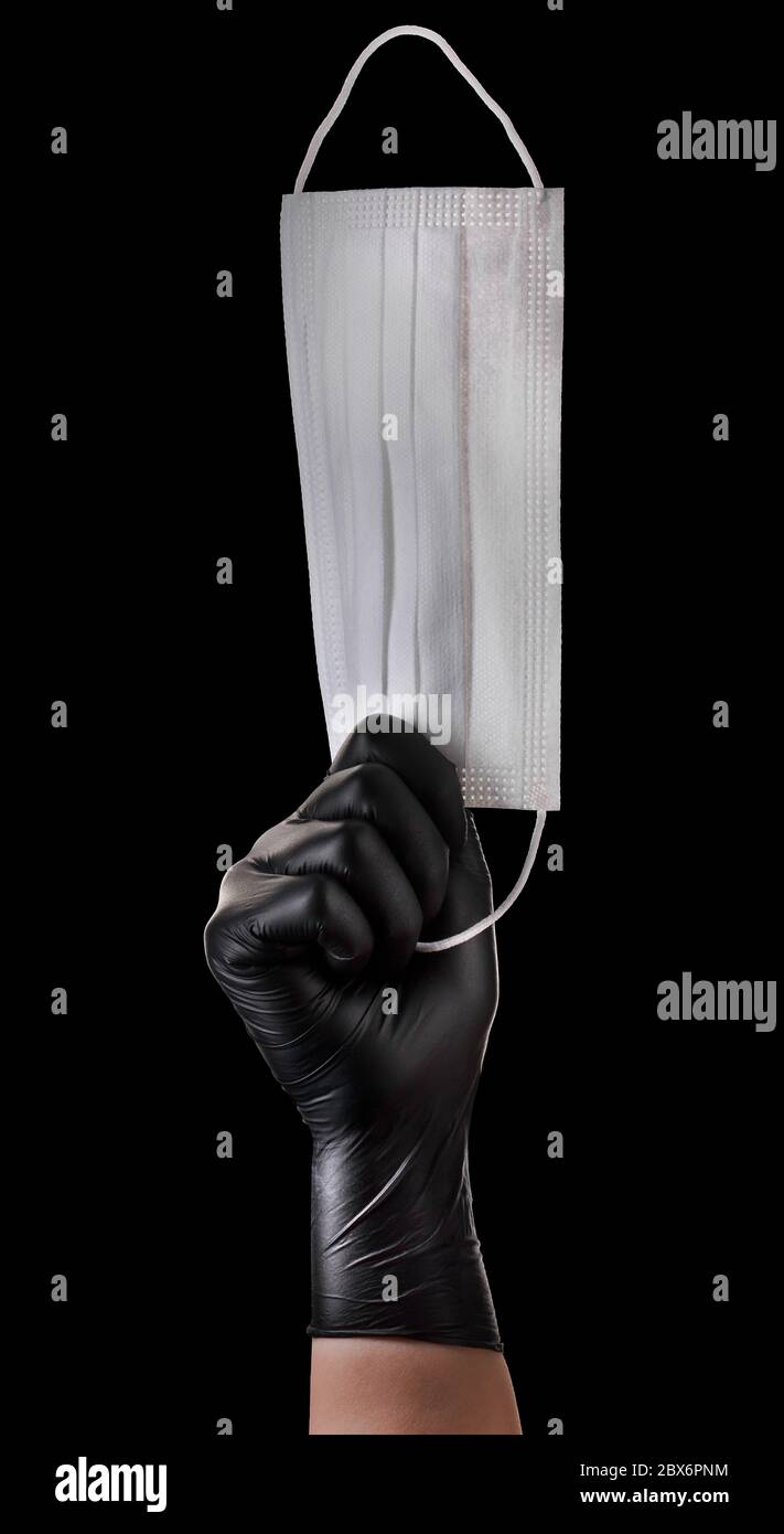 Hand in black gloves holding disposable face mask isolated on black ...