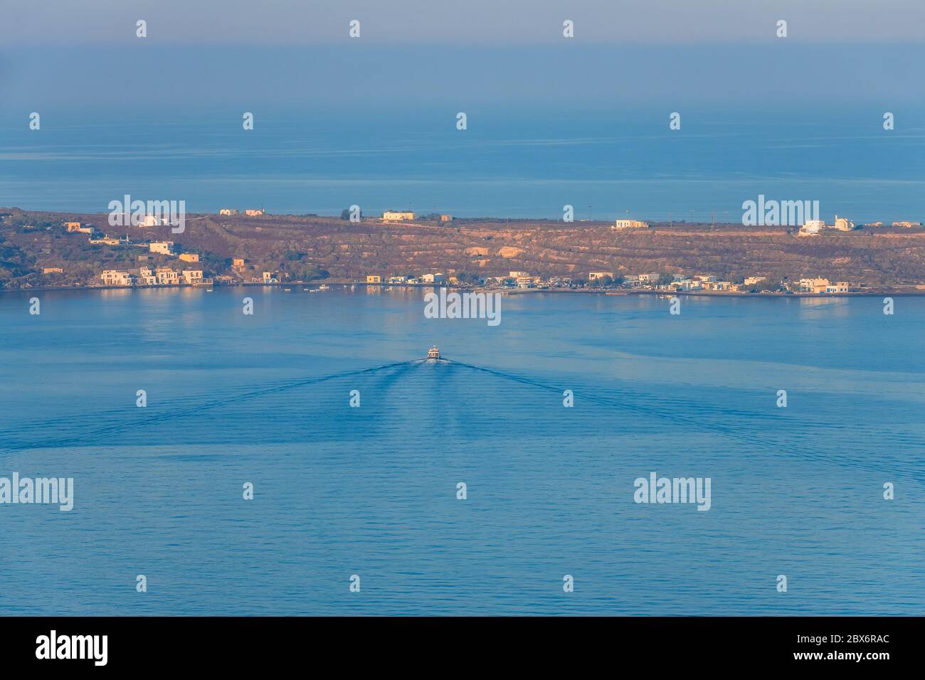 Narrow strip of shore without trees. A motor boat floats to the pier in quiet water. Aerial view Stock Photo