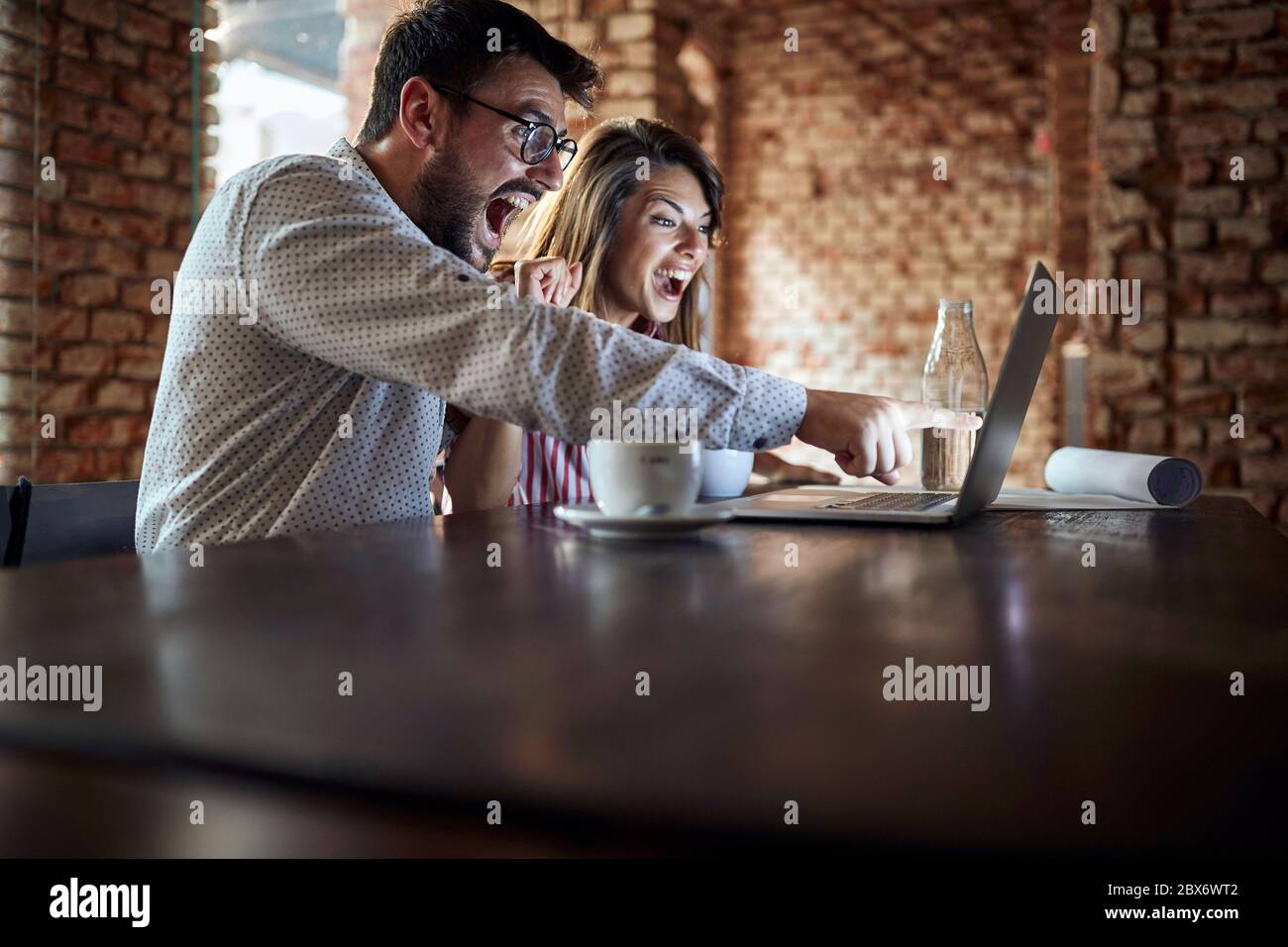 young caucasian couple delighted by content on laptop Stock Photo