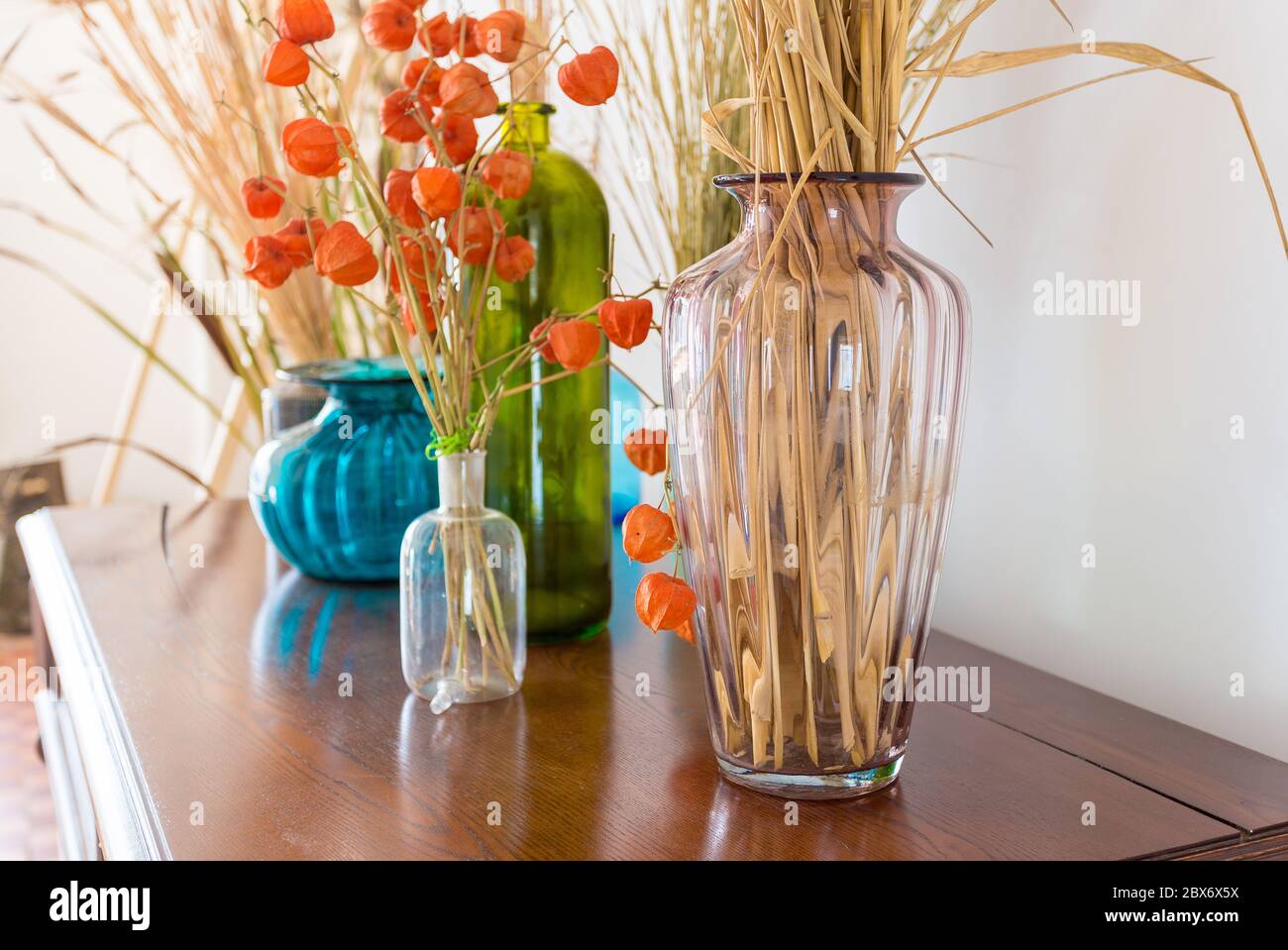 beautiful varied vases with dry plants on an old antique vintage mahogany chest of drawers Stock Photo