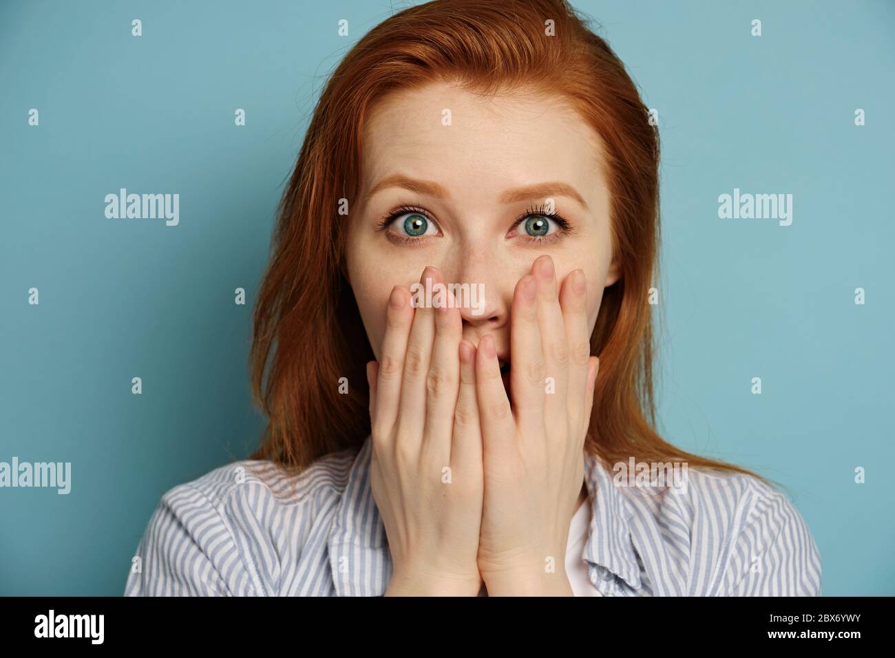 A redhaired girl in a striped shirt stands on a blue background and