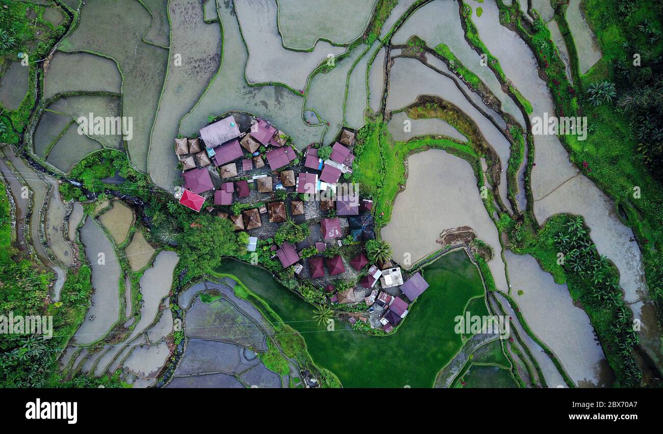 Aerial view on tiny community houses settlement surrounded by rice paddy fields in the mountains. Batad, Philippines. Stock Photo