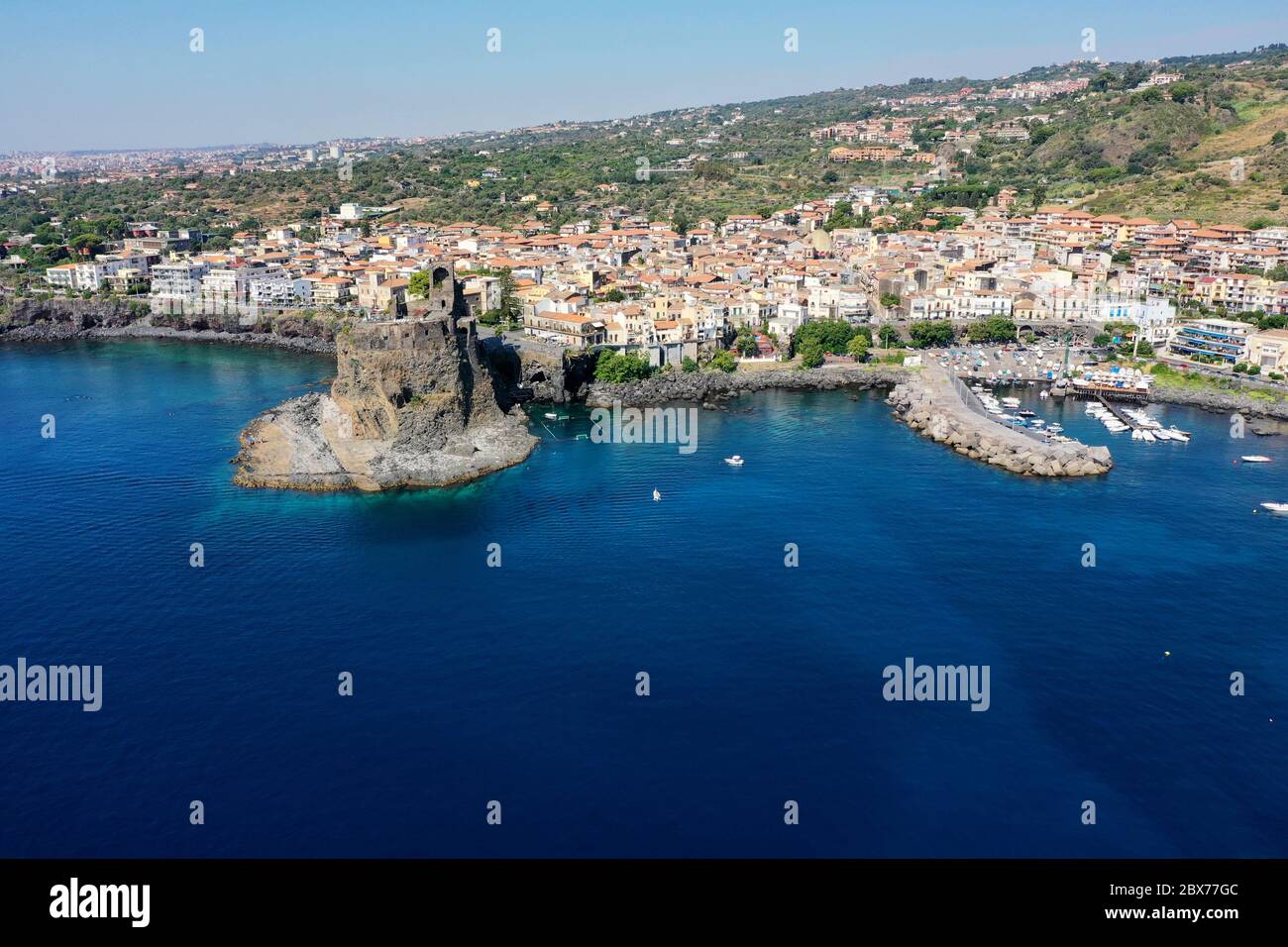 Acicastello seaport: View during the summer season of the city and of the clear blue seabed with Castle Stock Photo