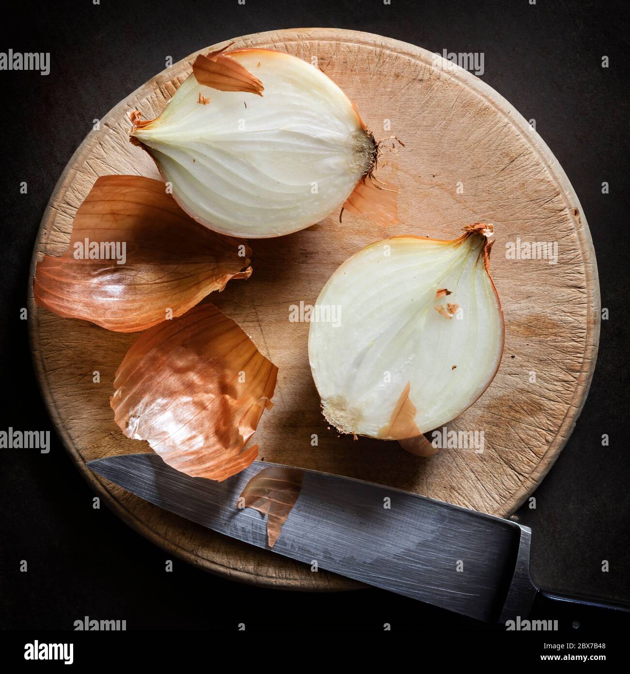 Cutting onions on round wooden vintage board.  Top view, on slate. Stock Photo